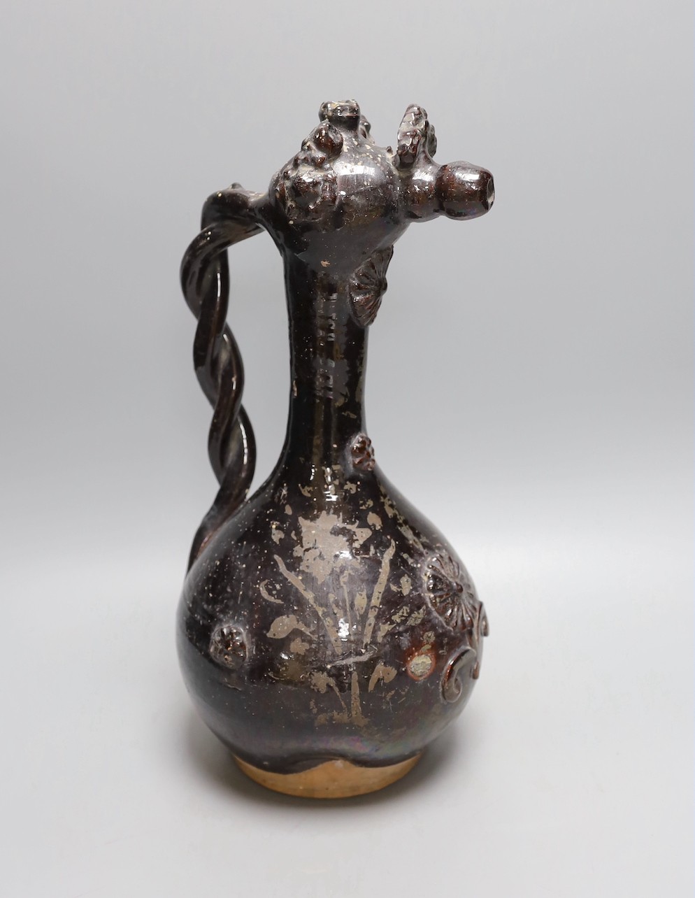 A primitive black glazed terracotta ewer with decorative headed spout and twisted handle - 38cm high